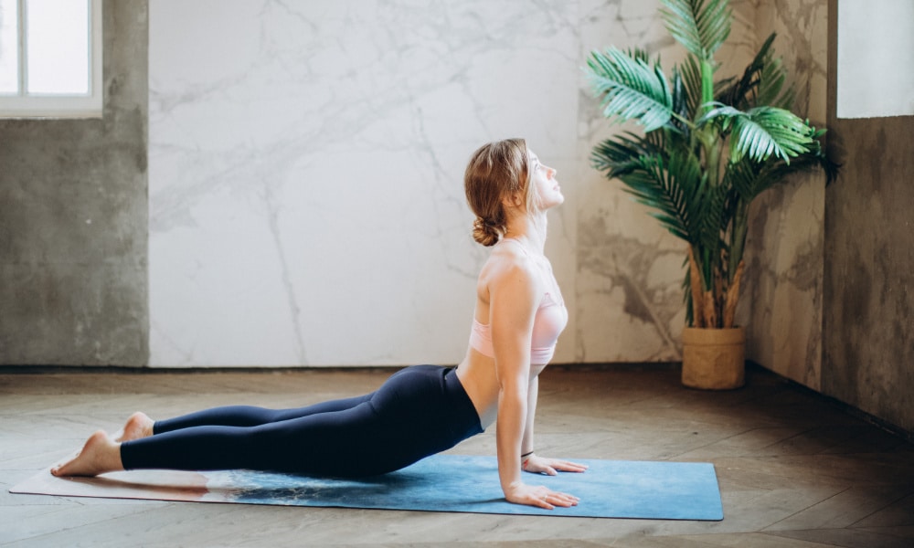 Woman practicing yoga on mat inside