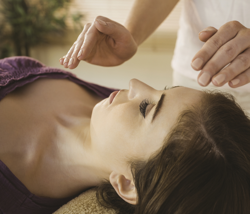 Professional Reiki healer doing reiki treatment to young woman